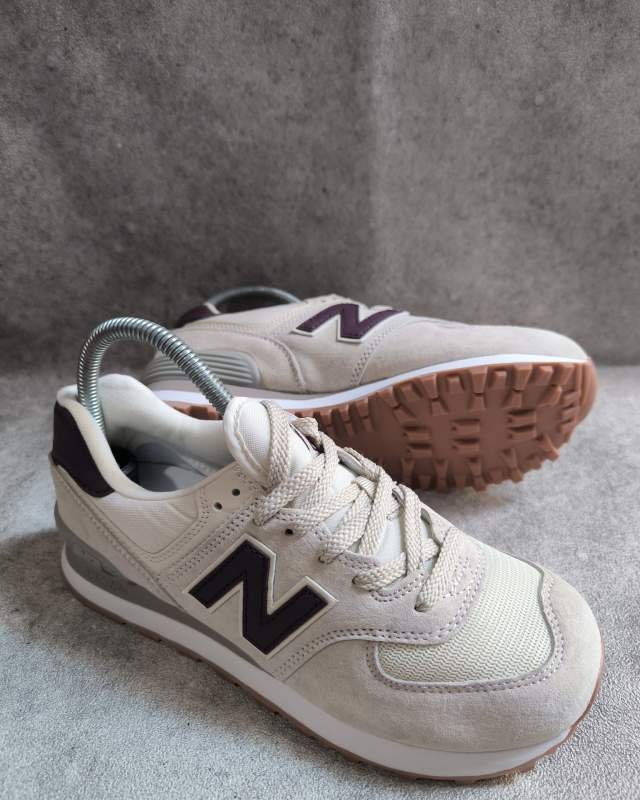 New Balance 574 (siluet klasik New Balance berbahan suede dan mesh dengan logo 'N' berwarna cokelat tua/hitam serta sol luar bergerigi gum sole)
