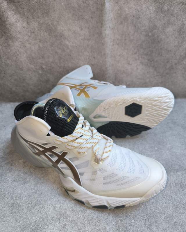 Asics Asics (sepatu olahraga basket/voli high-performance dengan logo Asics warna emas/gold di bagian samping, kerah pergelangan kaki yang tinggi, serta bantalan FlyteFoam)