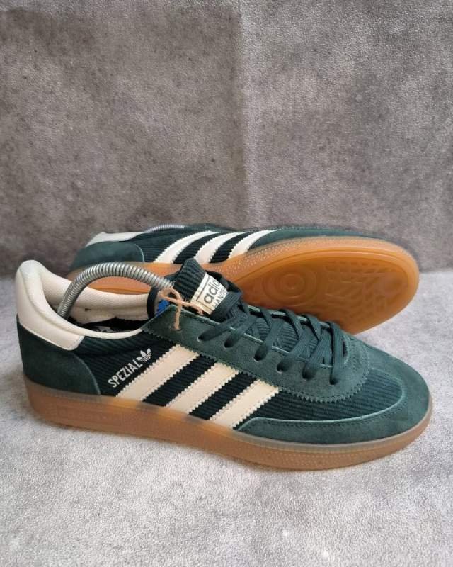 Adidas Adidas Handball Spezial (sepatu lifestyle/casual klasik berbahan suede hijau tua, dilengkapi tiga garis khas Adidas berwarna krem/off-white, sol karet gum cokelat, serta tulisan foil emas 
