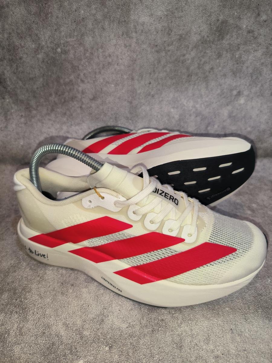 Adidas Adizero Evo SL berwarna wonder white dengan aksen garis merah yang mencolok