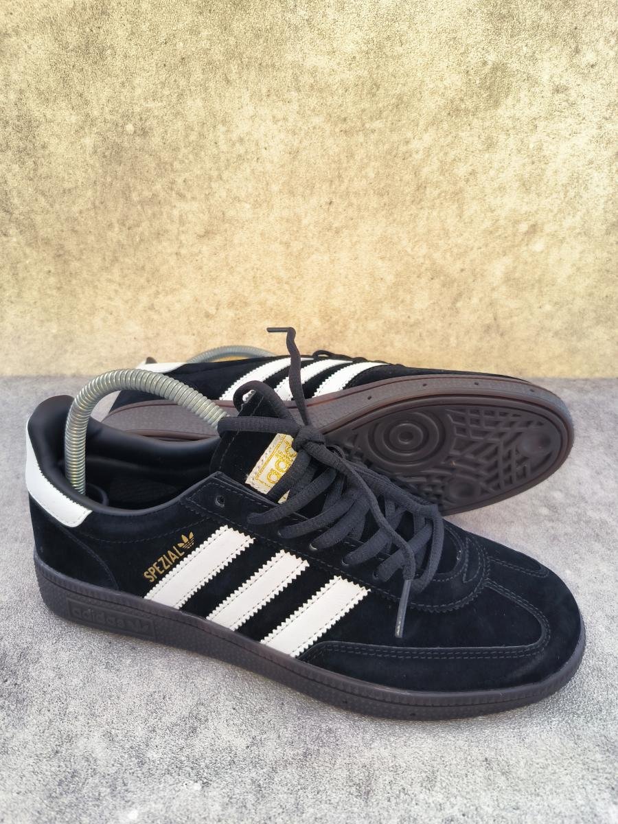 Adidas Handball Spezial berwarna hitam dengan aksen putih dan sol karet gum (Core Black/Cloud White/Gum).