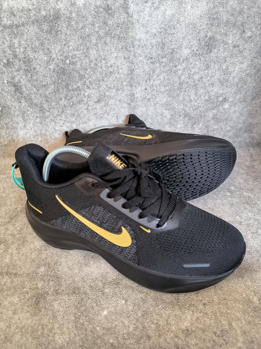 Nike Run Swift 2 dengan kombinasi warna hitam dan logo swoosh emas (Black/Metallic Gold).