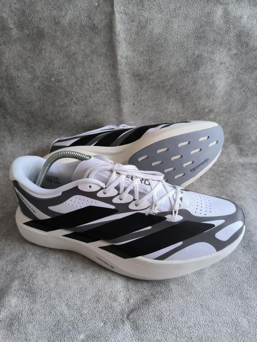 Adidas Adizero Evo SL EXO berwarna putih dengan aksen tiga garis hitam yang kontras di bagian sampingnya